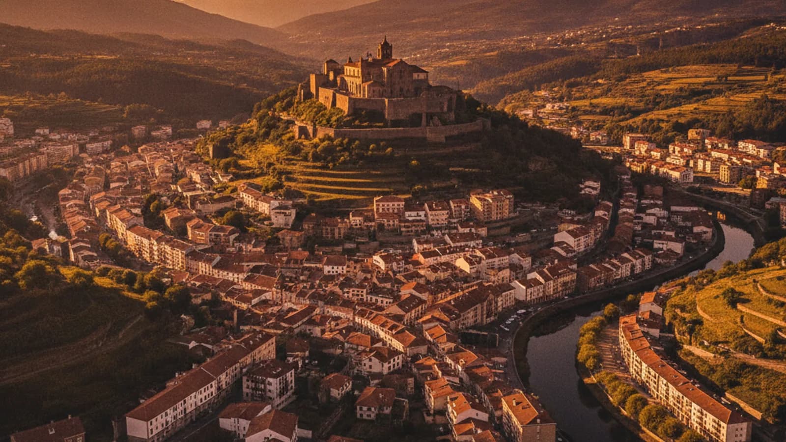 Vista panorámica de Monforte de Lemos con el Monasterio de San Vicente del Pino en lo alto de la colina, al atardecer, sobre el entramado urbano.