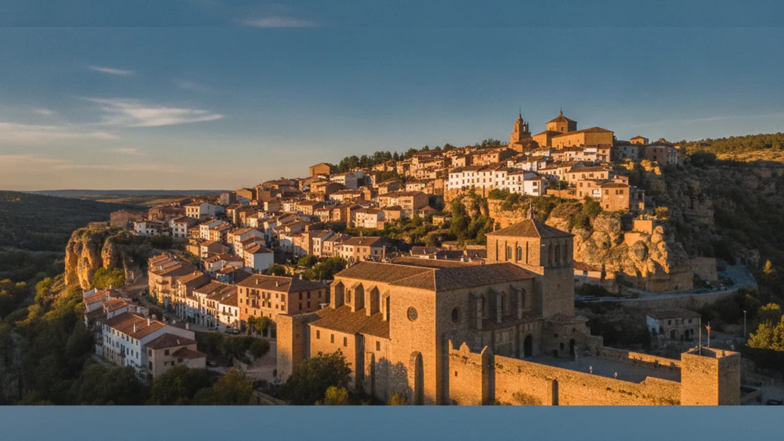 Una vista panorámica de Nájera con el Monasterio de Santa María la Real en primer plano y las casas trepando por la ladera rocosa, bajo un cielo azul.